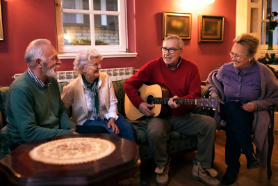 senior man playing guitar while his friends listening